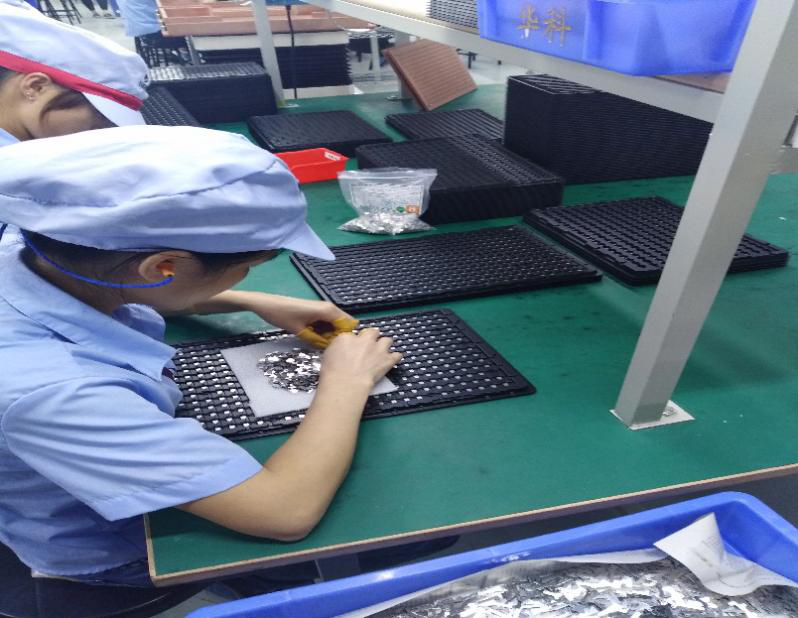 操作工在对微小零件进行吹塑盘的摆入作业